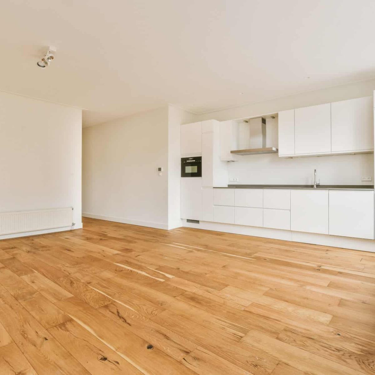 a-spacious-empty-room-with-a-corner-kitchen-on-parquet-floors-1.jpg
